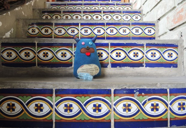 Edgar is sitting on the steps. The steps are concrete with blue and white tiles on the edges.