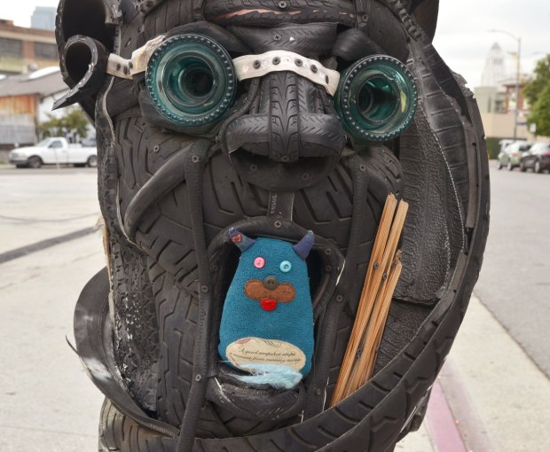 a telephone pole has been decorated with tires that have been made into faces. Edgar is sitting in the mouth of one of these faces