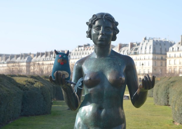 edgar is standing in the open hand of a statue of a naked women in a park in Paris 
